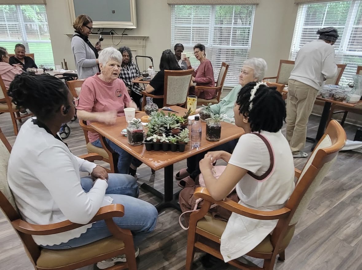 Young and old people sitting around a table building terrariums.